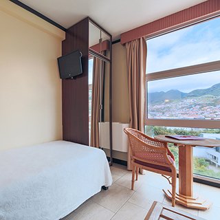 quarto com uma cama e vista para montanha e machico na Ilha da Madeira